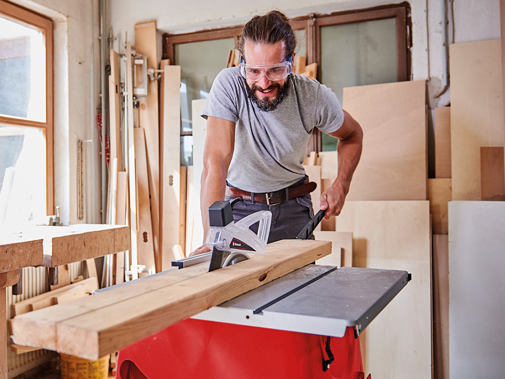 A man cuts a board in two parts with a table saw