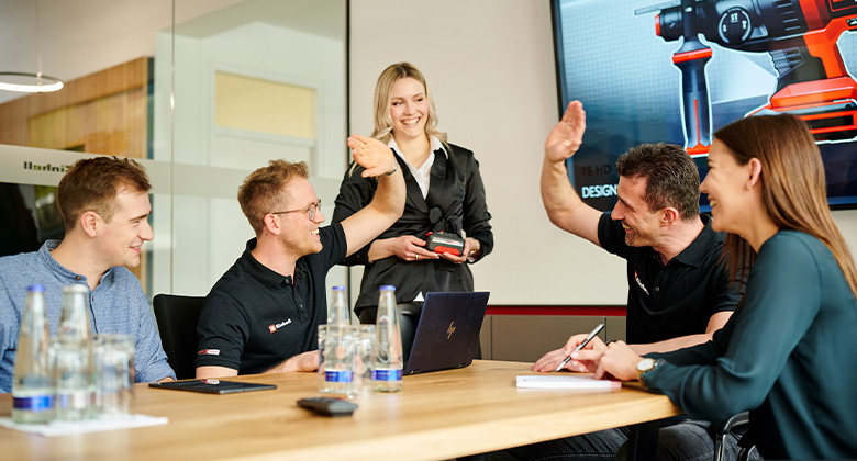 A Group of people laughing at each other in a meeting room.