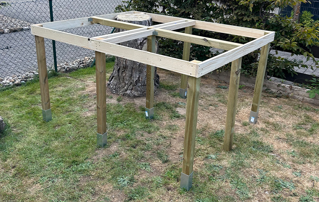 Die Holzkonstruktion des Podests steht auf acht Pfosten, in der Mitte ein abgesägter Baumstumpf.