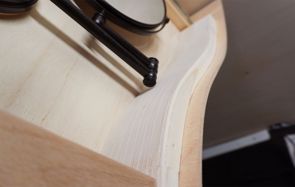 Close-up of the cabinet’s curved inner edge with a mounted mirror arm.