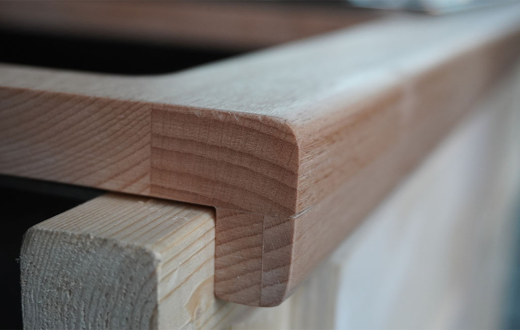 Detailed close-up of a smoothly sanded, rounded wooden edge of a countertop.