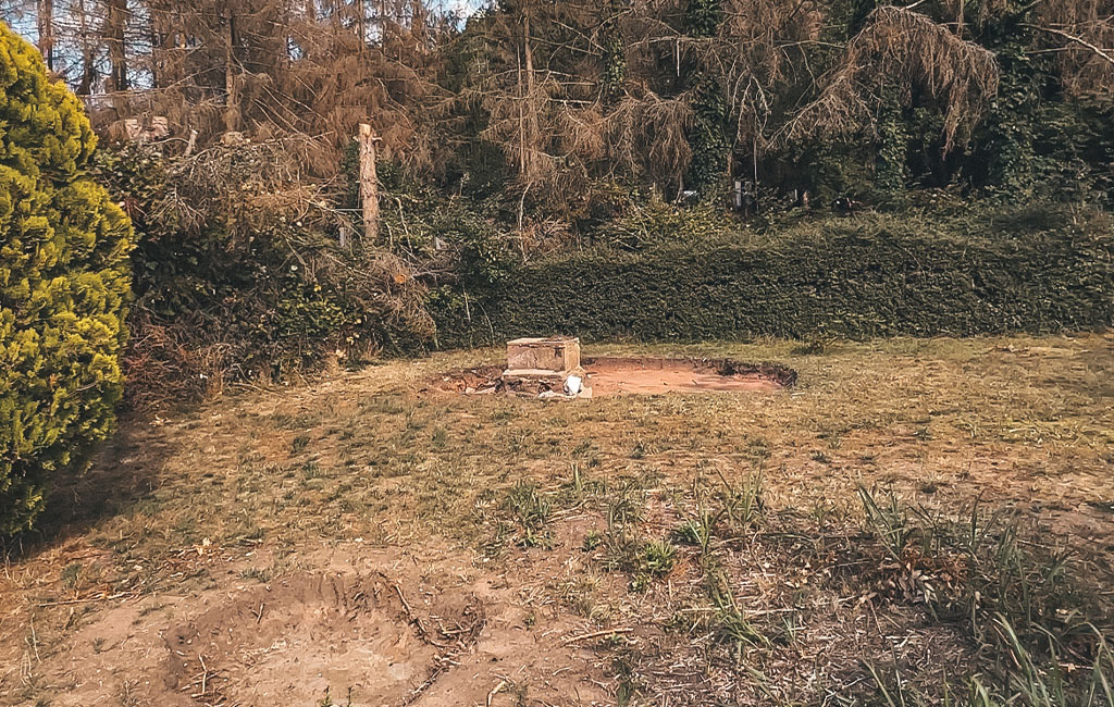 An empty lawn area with a small, old concrete slab in the center.