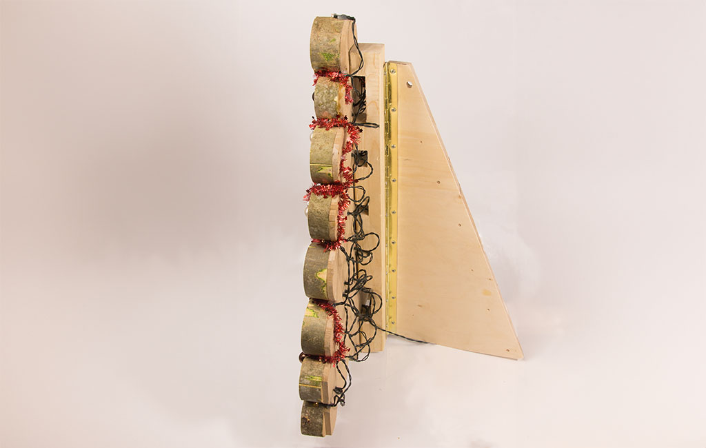 Seitenansicht der fertigen Konstruktion: Holzscheiben mit Lichterketten, befestigt auf einem Holzständer.