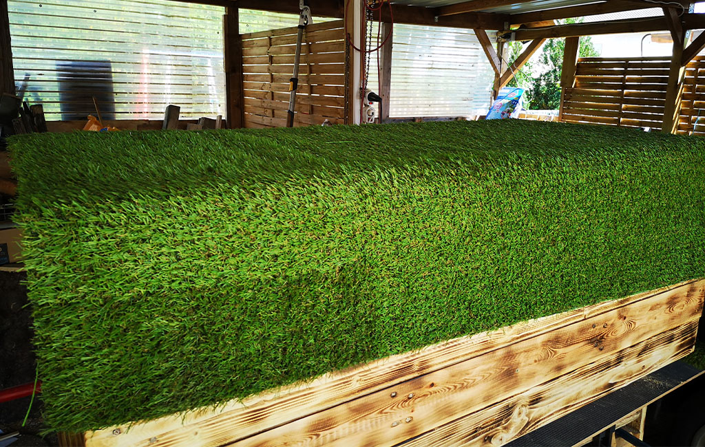 Nahaufnahme der Holztruhe mit geschlossenem Deckel. Der Deckel ist mit grünem Kunstrasen beklebt.
