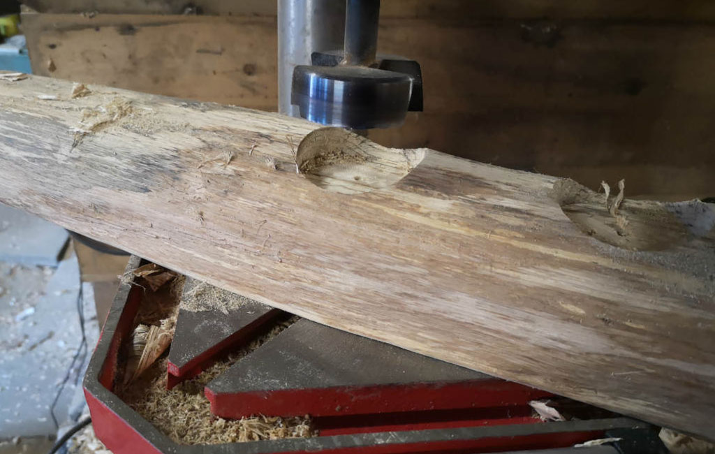 Using a drill press to make holes in a wooden plank for a DIY Christmas decoration project