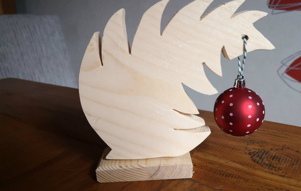 Wooden leaf-shaped decoration with a red Christmas ornament