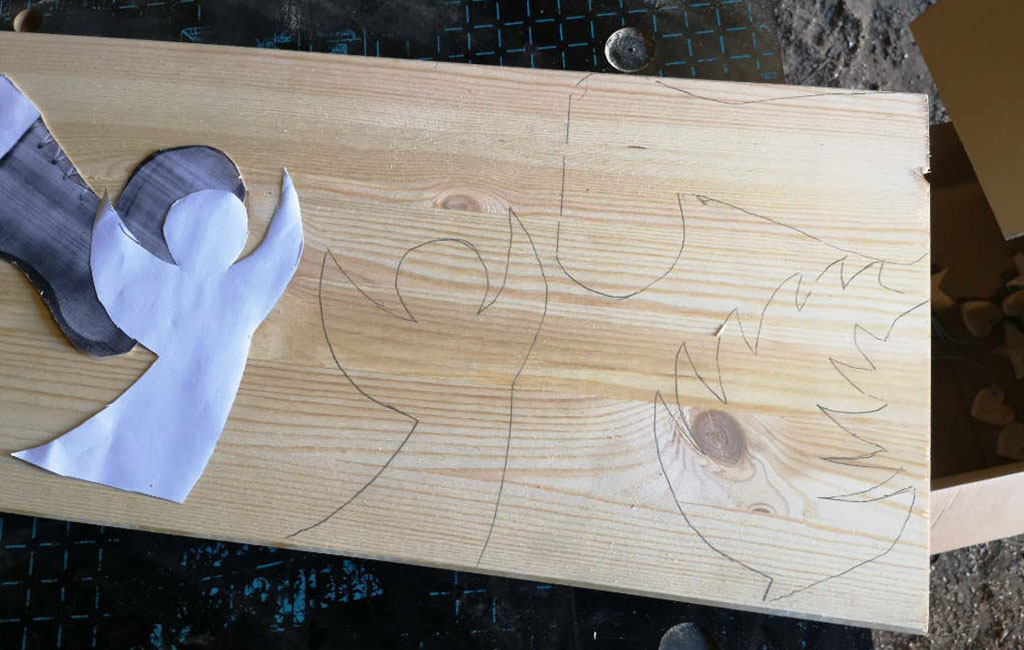Sketching the design of a Christmas decoration onto a wooden board before cutting