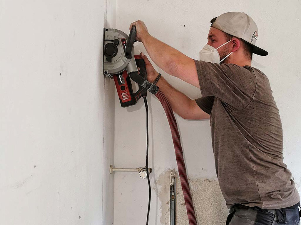 Person aligns a drill guide on a wall and secures it for precise drilling.