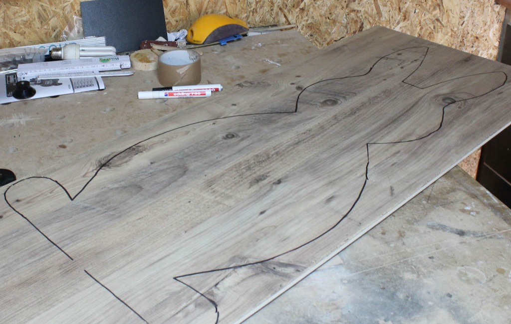 Bunny outline drawn on a wooden board, with a marker and crafting materials beside it.