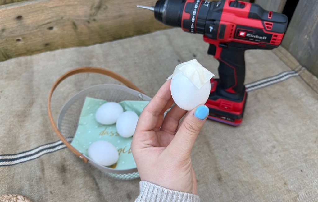 Egg with tape held in front of an Einhell cordless drill.