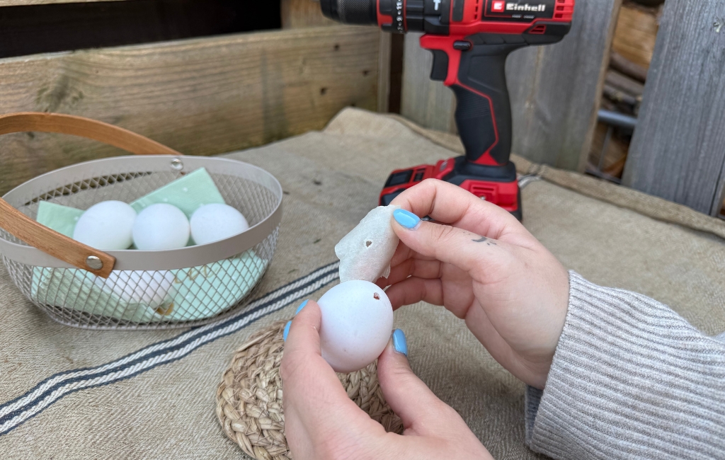 Hands carefully peeling an egg, with an Einhell cordless drill in the background.
