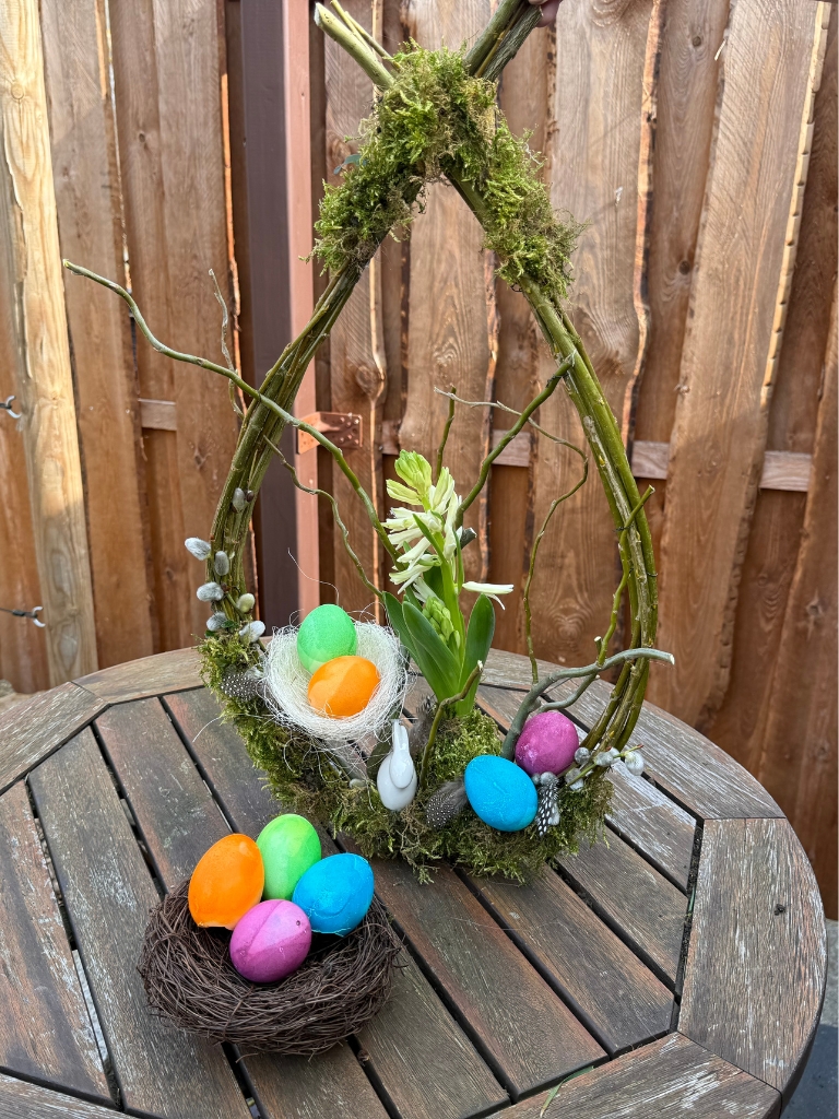 Close-up of the Easter wreath with colorful eggs, moss and flowers.