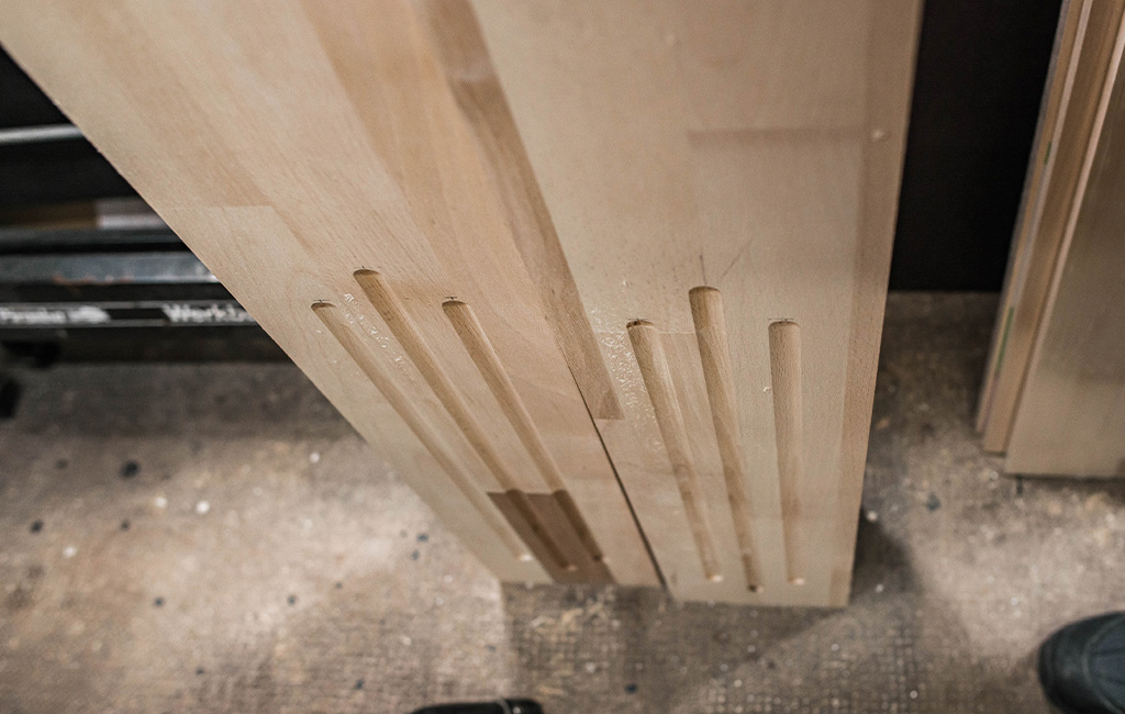 Two wooden boards with routed grooves stand upright on the floor.