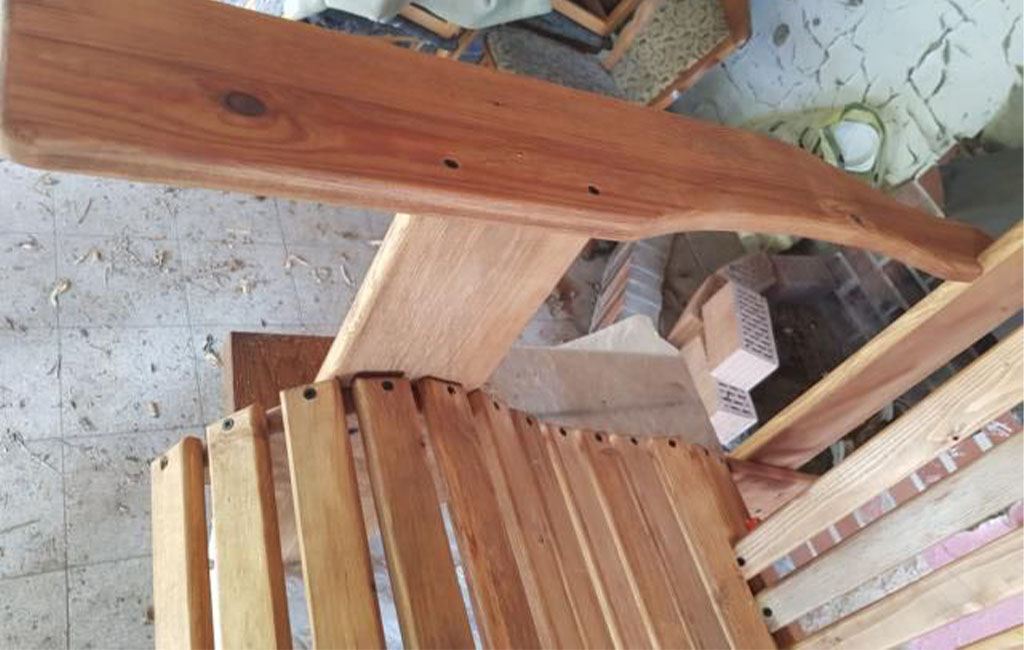 Die geschwungene Armlehne eines Holzstuhls ist von oben zu sehen, sie ist bereits montiert.