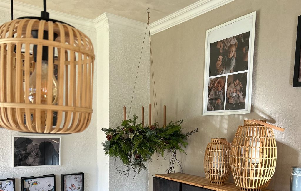 The hanging Advent wreath with four candles is suspended by strings from the ceiling above a sideboard.