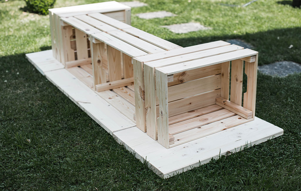 Three wooden crates are arranged on a wooden panel as the base structure of the garden bar.