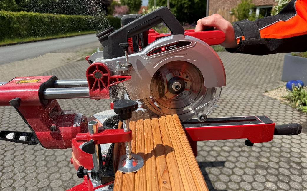 Eine Kappsäge schneidet Holzbretter für den Bau eines selbstgebauten Pflanztisches zu.