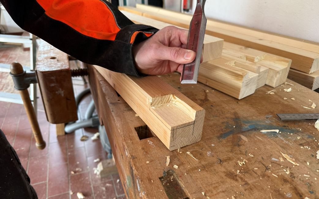 Eine Person bohrt Löcher in Holzleisten für den Bau eines selbstgebauten Pflanztisches.