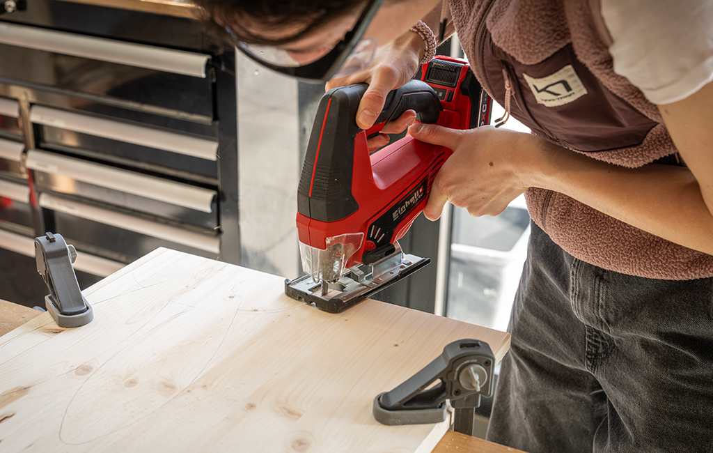A person cuts a rabbit shape out of a wooden board using a jigsaw.