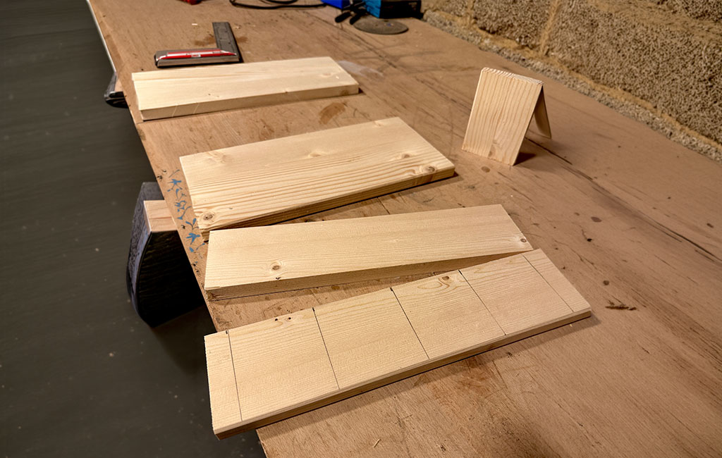Several cut wooden boards with marked lines placed on a workbench in a workshop, prepared for further cutting and assembly.
