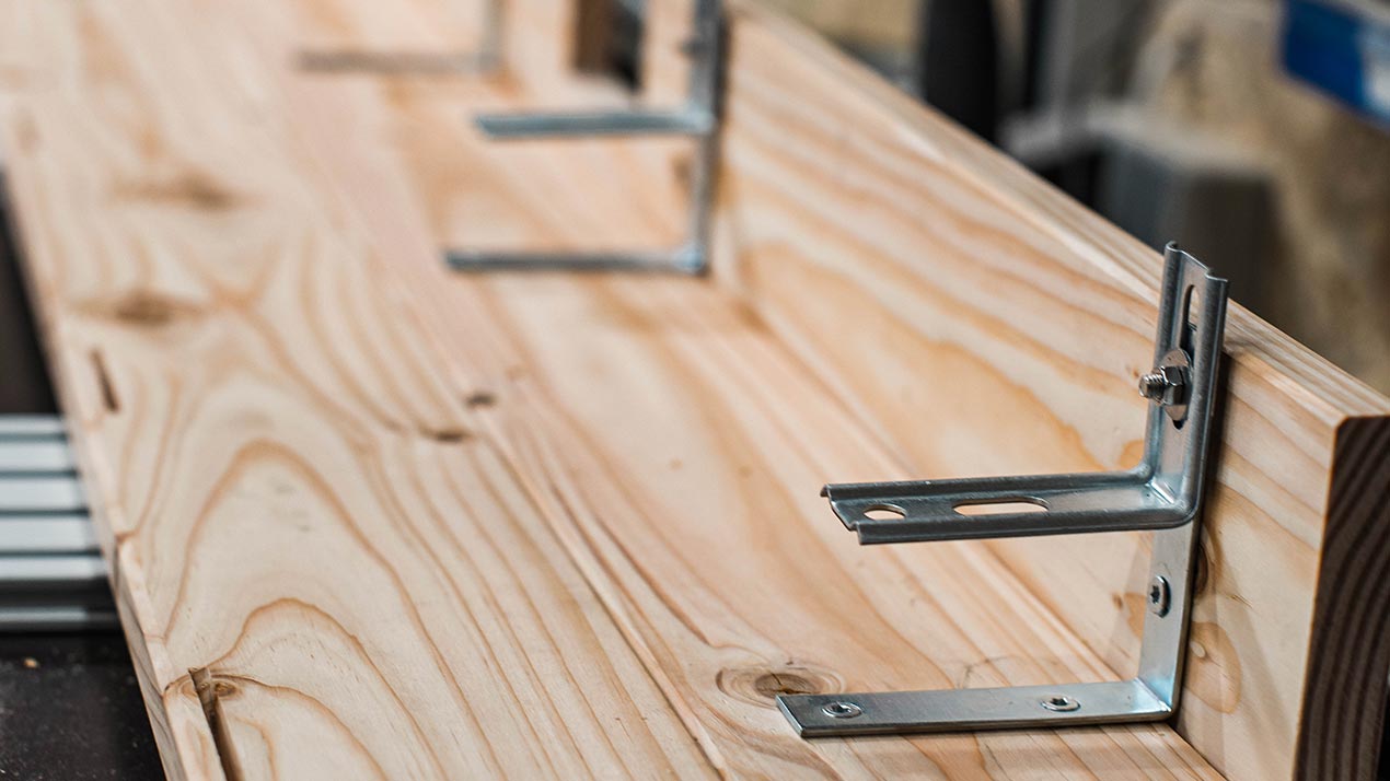 Metal brackets attached to a wooden panel.