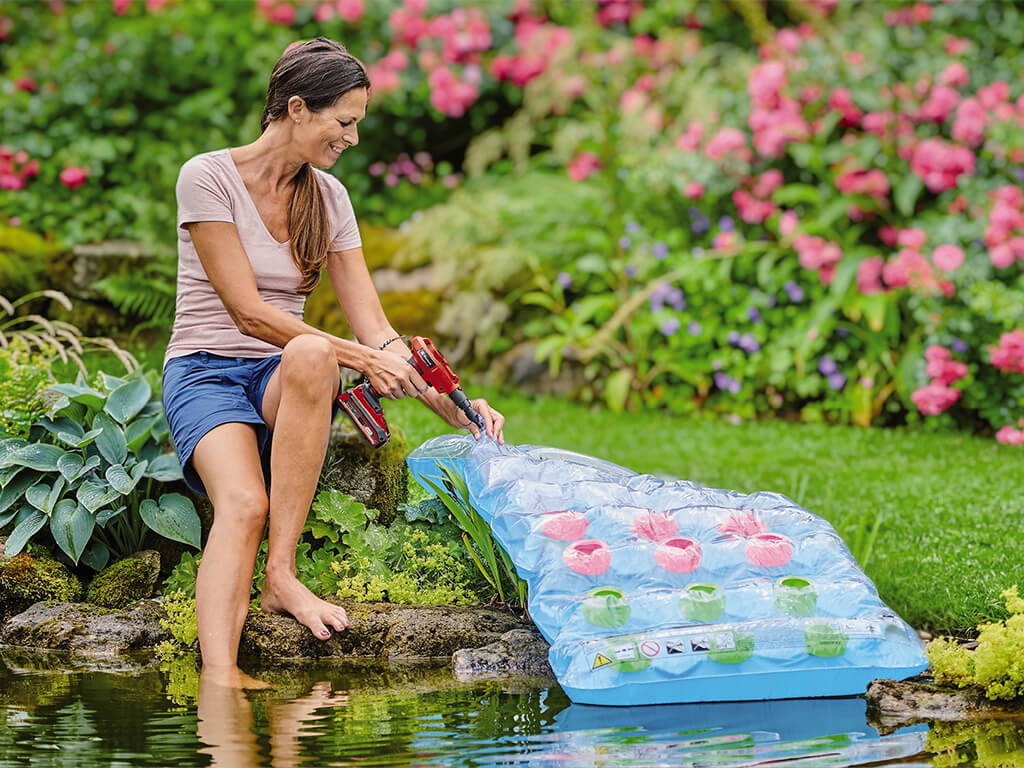 A woman inflates an air mattress with the help of the Einhell cordless air pump.