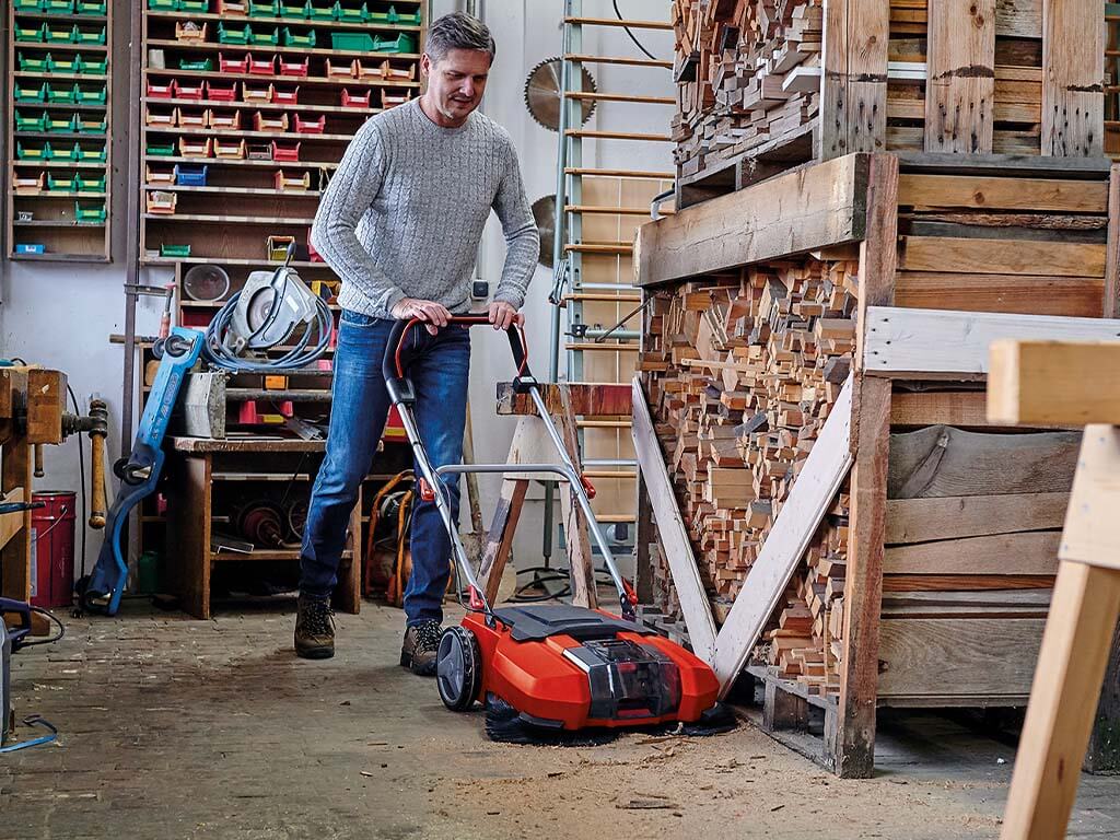 a man sweeps his workshop with the Einhell sweeper