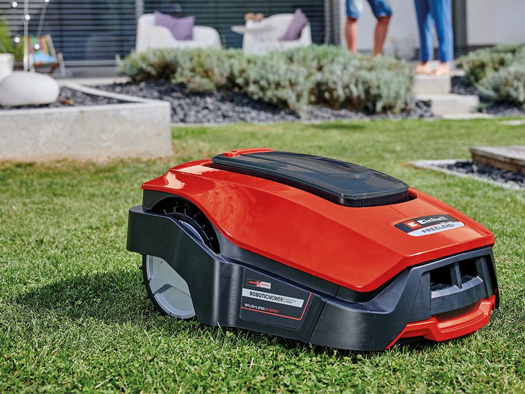 A close-up of a robotic mower on a green lawn in a garden.