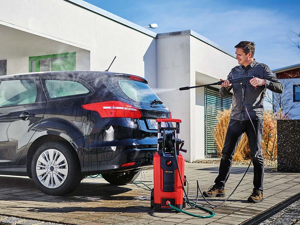 a man cleans his car with a pressure washer