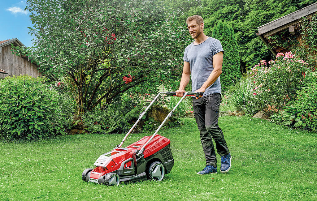 A man mows the lawn in his garden with an Einhell lawn mower