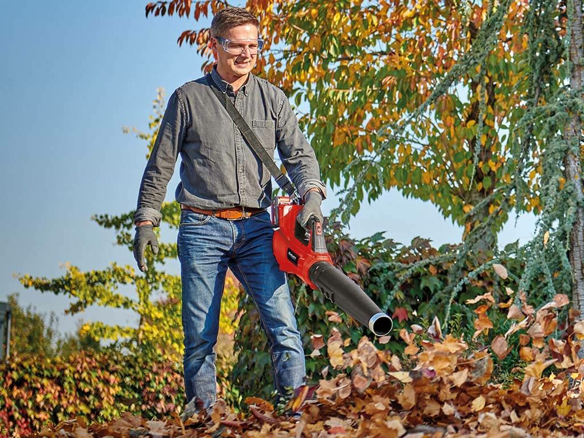 Ein Mann bläst Laub mit einem Einhell Akku-Laubbläser weg.