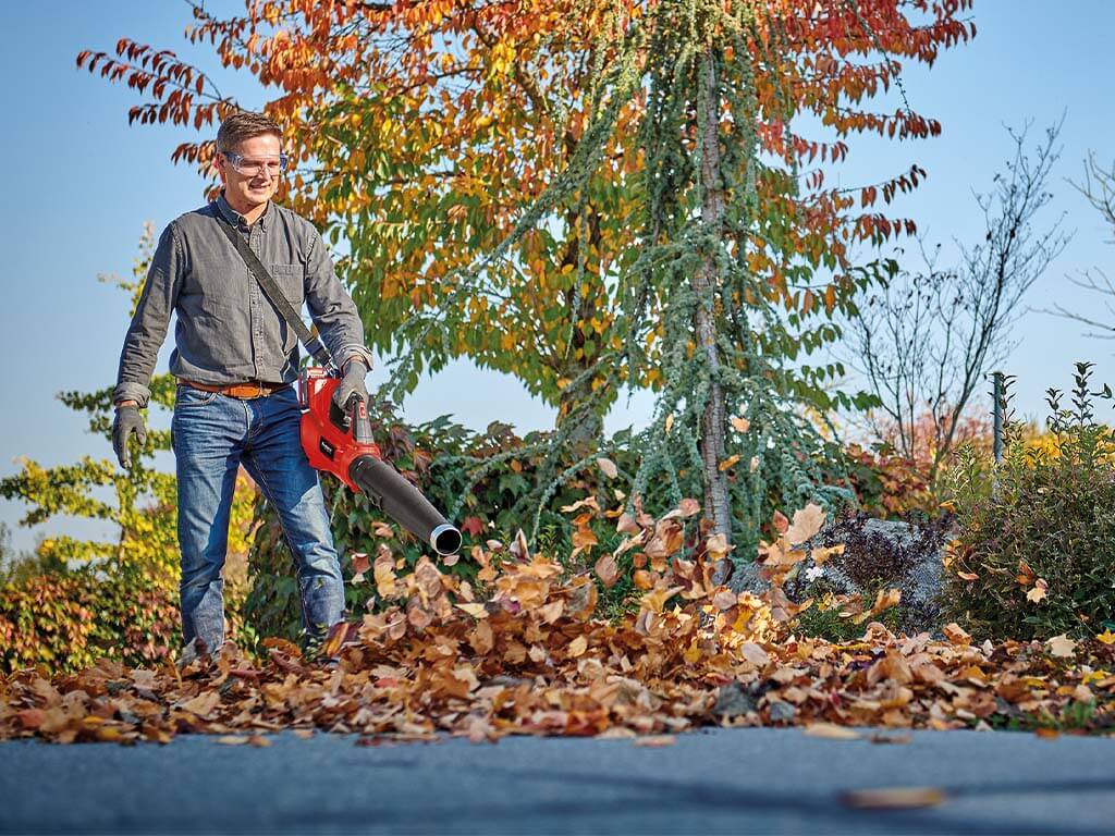 a man blows away leaves with a leaf blower