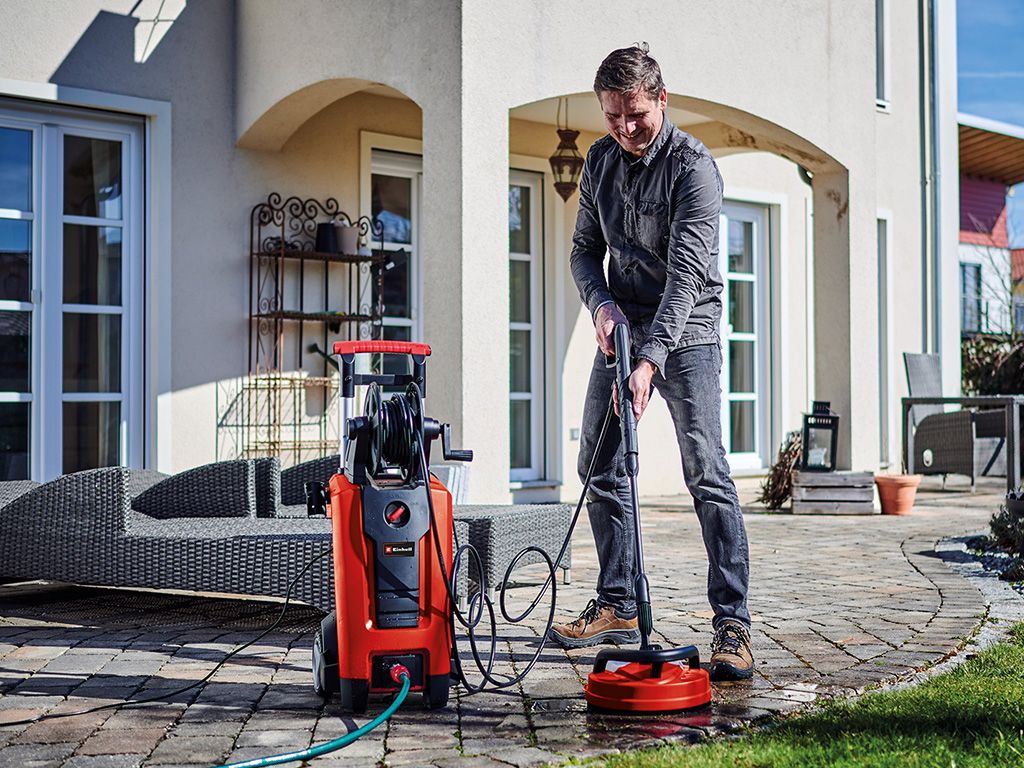 a man is cleaning the stone tiles of his terrace with a high pressure cleaner