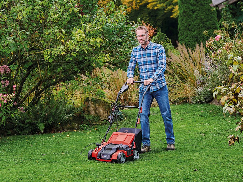 Man scarifying the lawn in the garden with an Einhell cordless scarifier