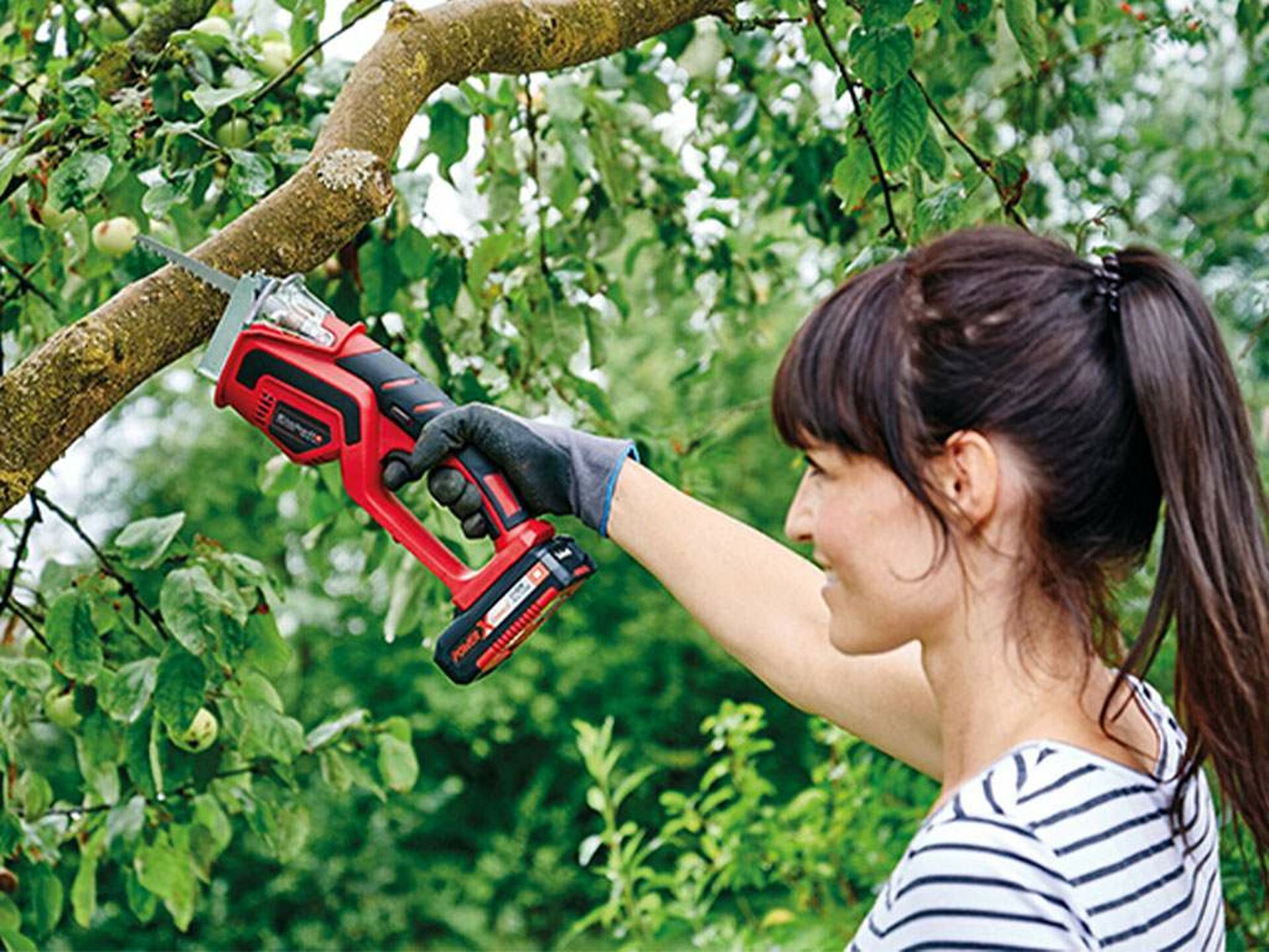 a woman cuts a branch with the branch shears