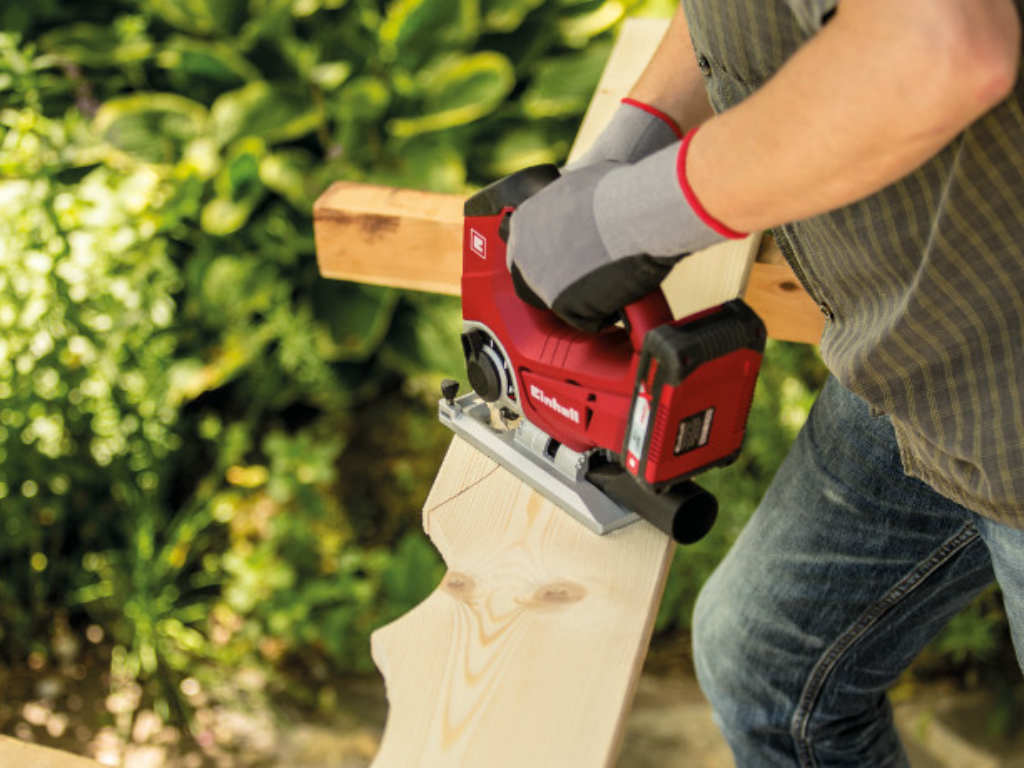 A wooden board is cut with a jigsaw