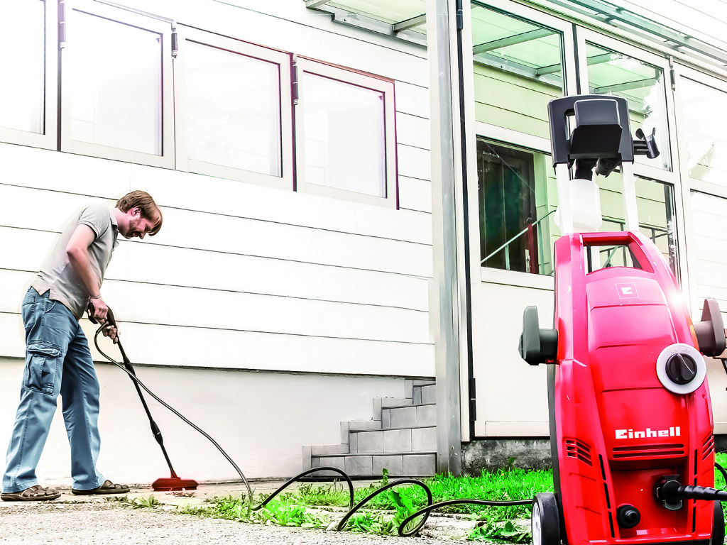 A man cleans the floor with a high-pressure brush