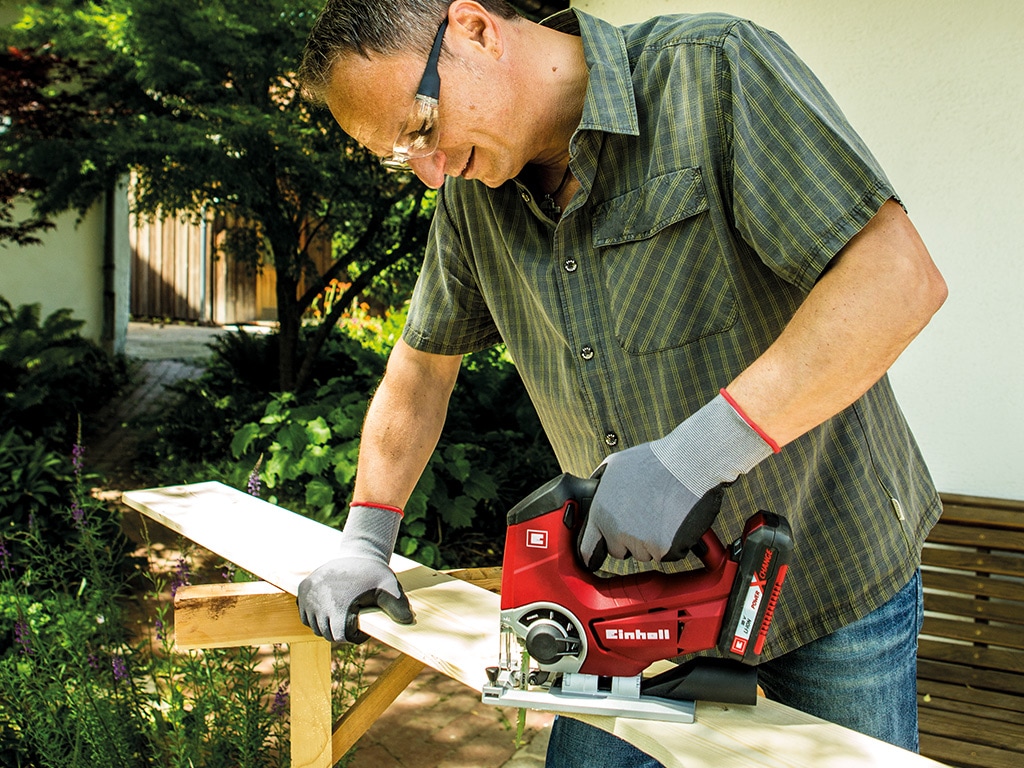 A man cuts a wooden board with a jigsaw