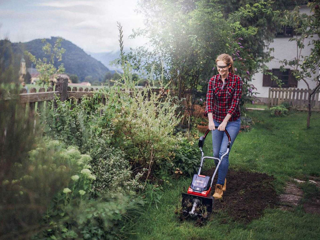 A woman chops the ground with a tiller