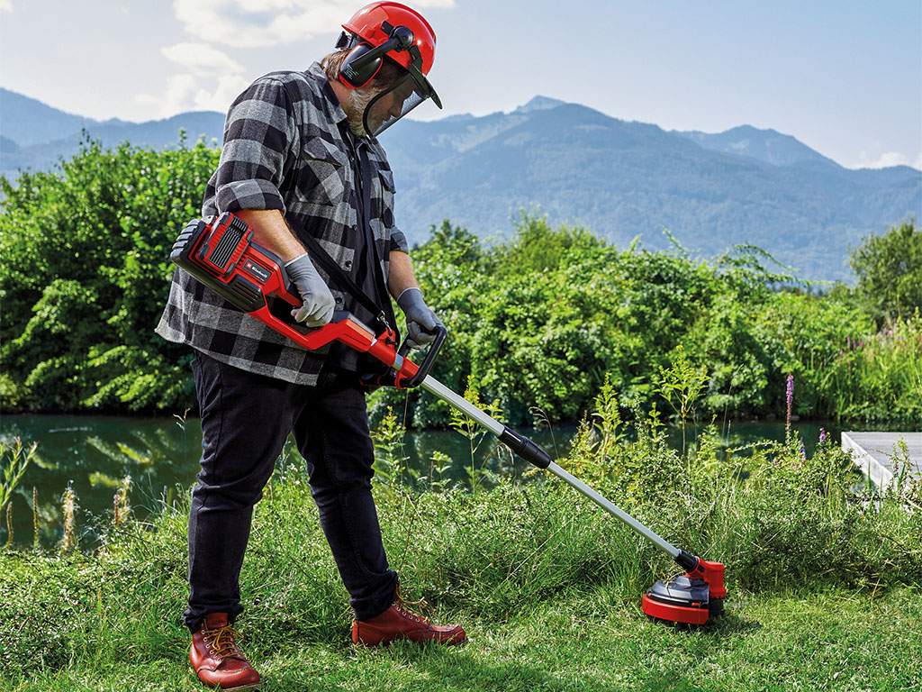 A man mows the grass with a brush cutter