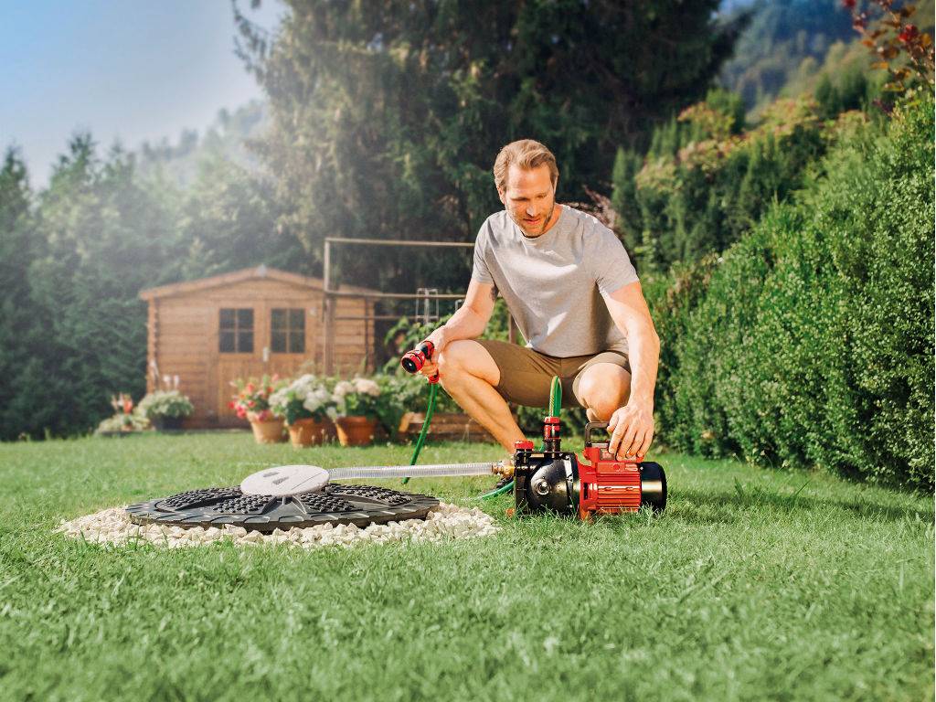 man with water hose in hand and water pump in front of him