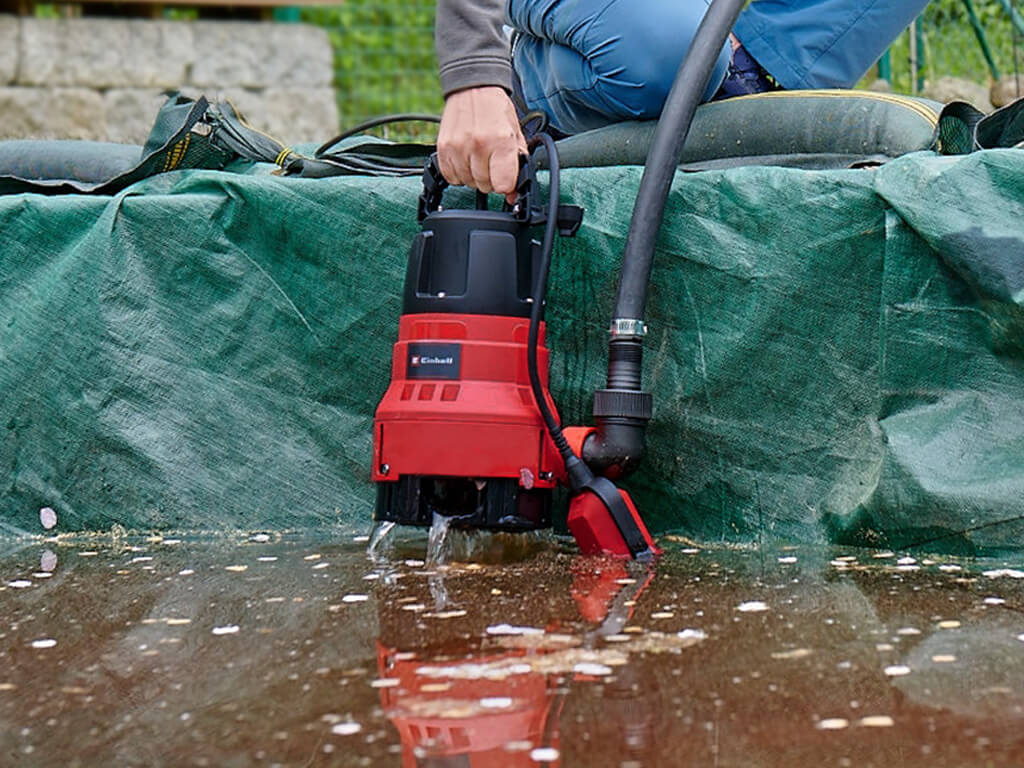 Eine Einhell Schmutzwasserpumpe wird aus dreckigem Wasser gezogen.