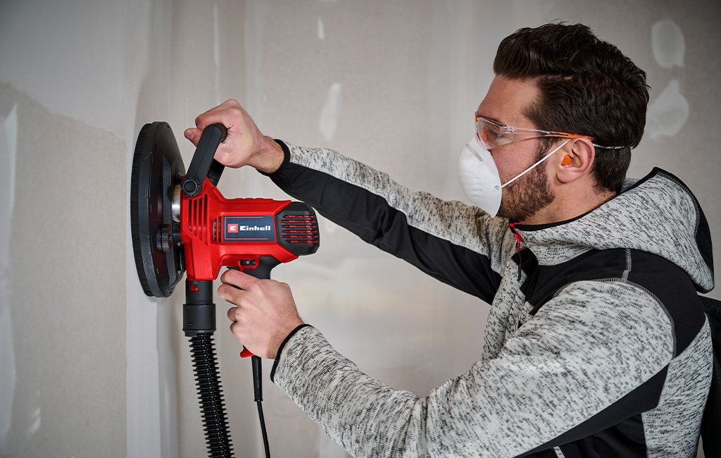 Man sanding wall in drywall construction with drywall sander