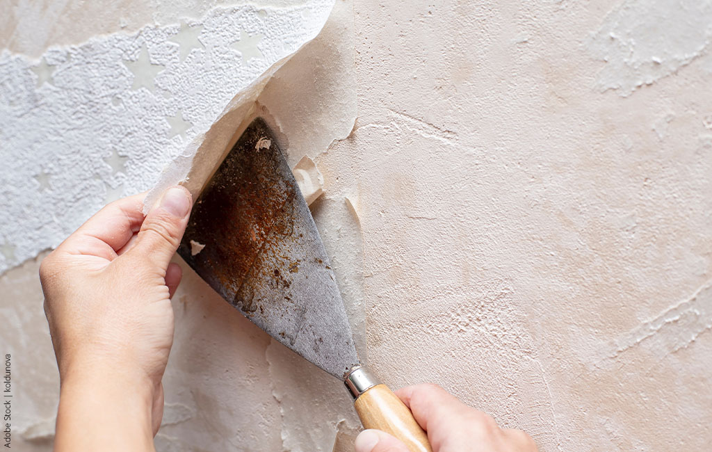 Old wallpaper is scraped off a wall