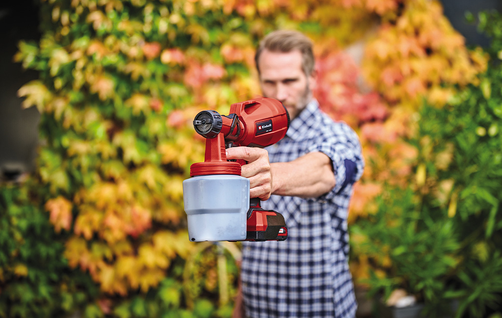 A man holding a paint spray system in his hand
