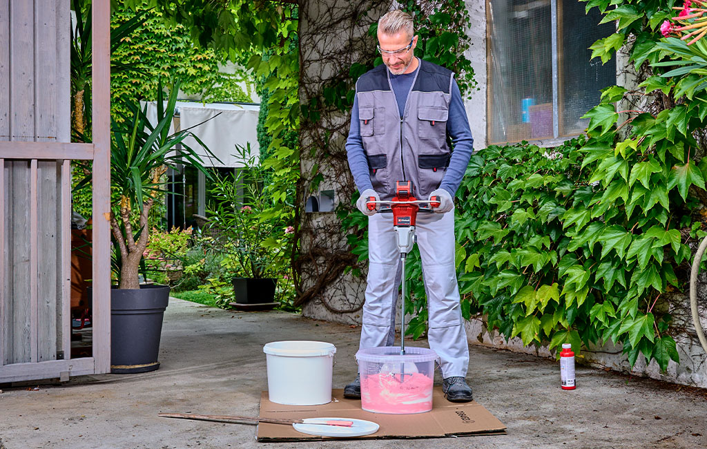 A man mixing wall paint with a paint mixer.