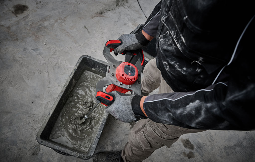 Ein Handwerker mischt mit einem Einhell Rührwerk Fliesenkleber in einer Wanne an.
