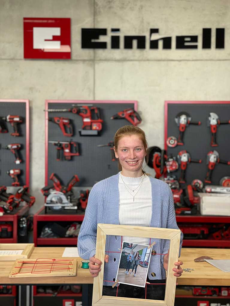 trainee holds wooden frame with a photo of himself and his godfather