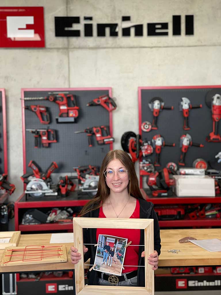 trainee holds wooden frame with a photo of himself and his godfather