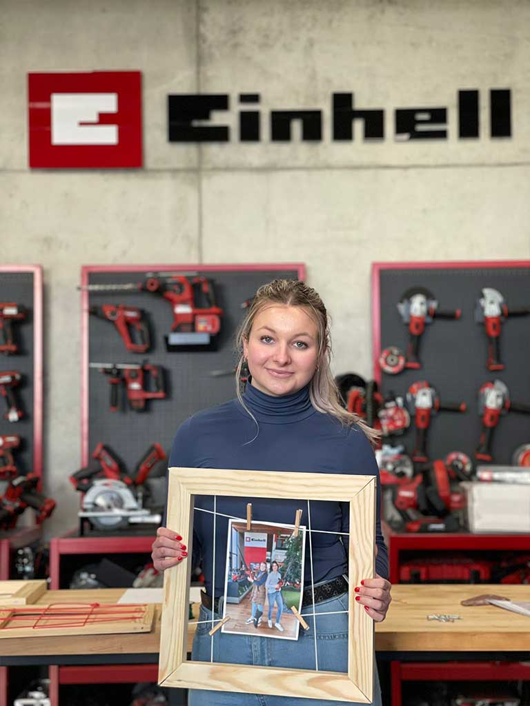 trainee holds wooden frame with a photo of himself and his godfather